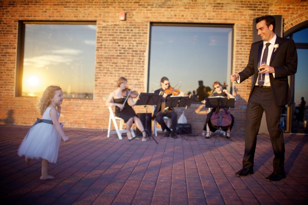 groom and flower girl dancing with string trio